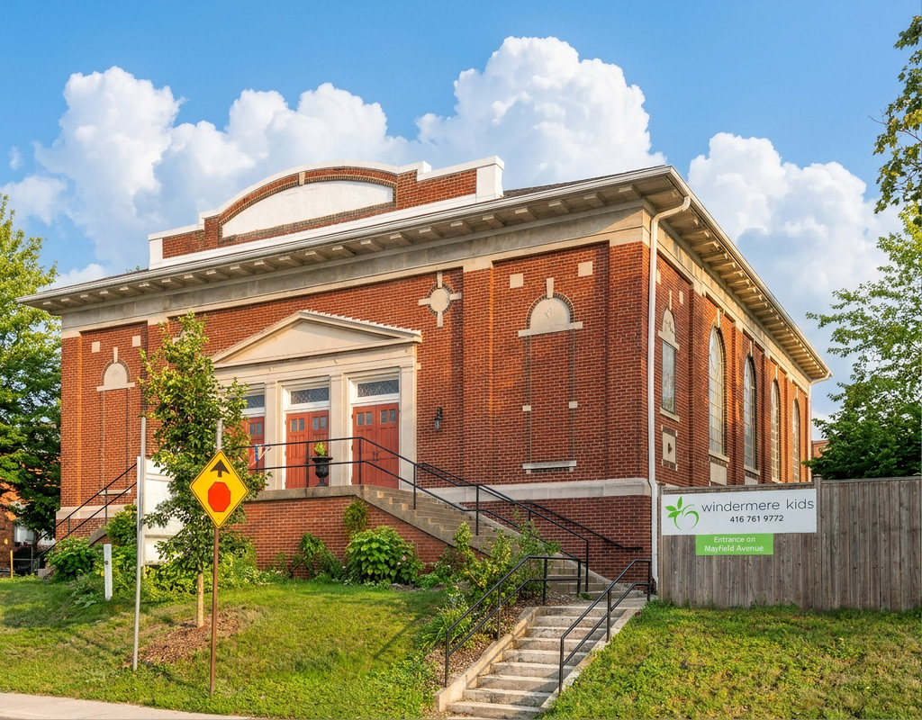 An exterior shot of the church where Windermere Kids is located within. Windermere Kids signage is affixed to the fence. Mature trees frame the photo.